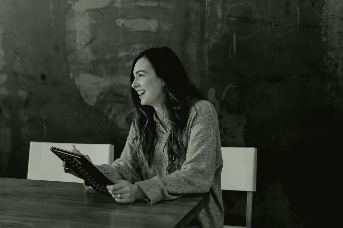 Profesional sonriendo durante una conversación, con una tableta en la mano